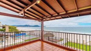 A balcony with a view of the beach and pool area.