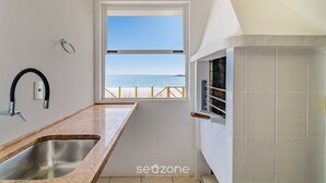 A kitchen with a view of the sea, a window, and a tiled wall.