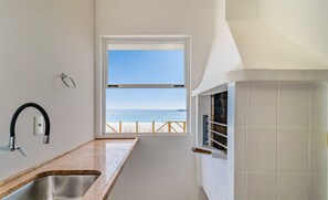 Eine Küche mit Meerblick, einem Fenster und einer gefliesten Wand.