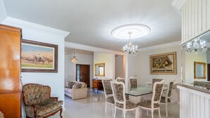 A dining area with a glass-top table, ornate chairs, and a chandelier. - Duplex W/pool 800m From the Beach in Jurere Dme025 (Florianópolis)