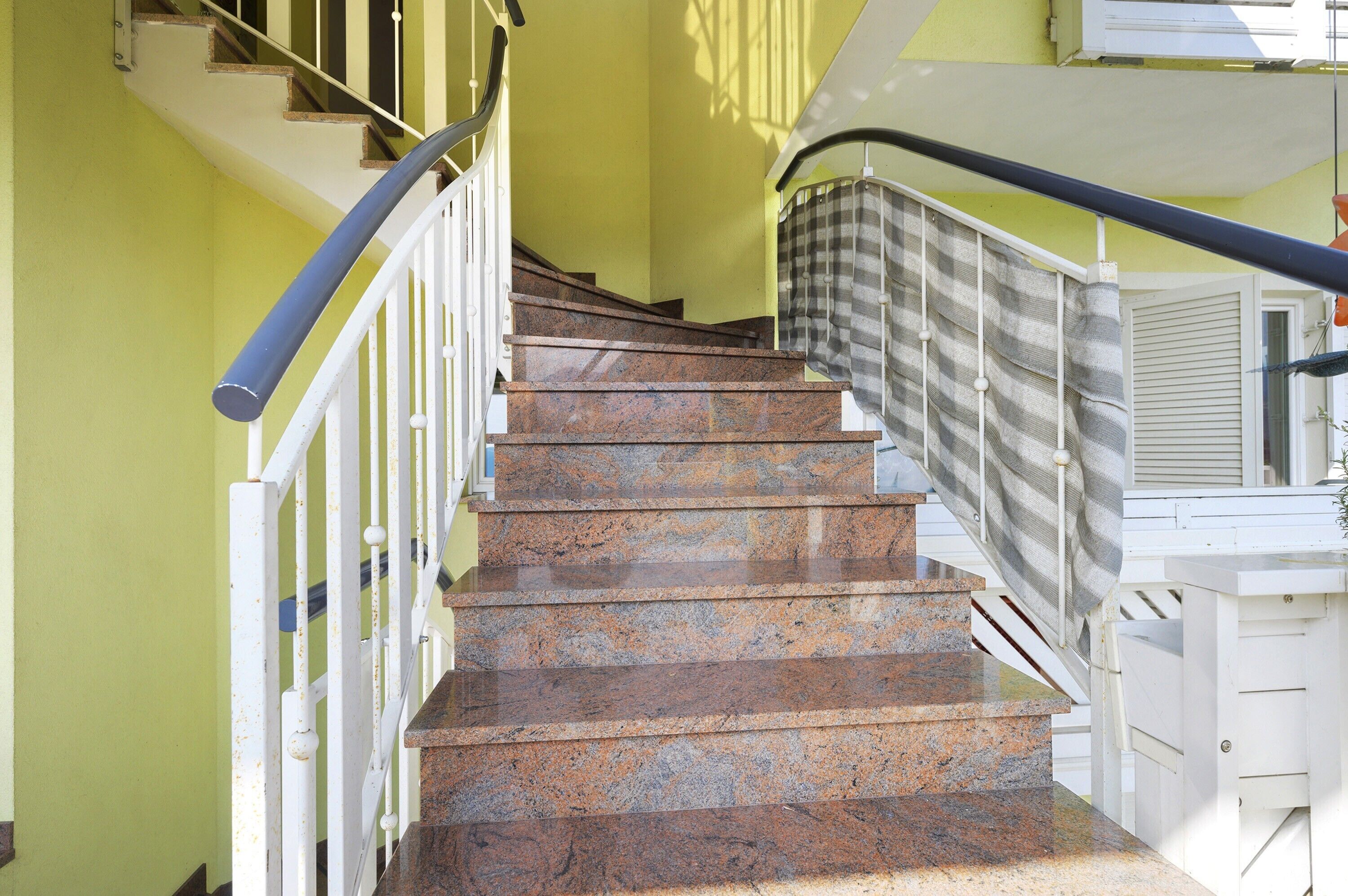 A staircase with a white railing and a checkered curtain.