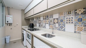A kitchen with a tiled backsplash, a sink, a stove, and a washing machine. - Apartment With Barbecue Near the sea Dov108 (Florianópolis)