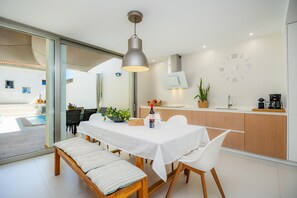 Een moderne eetruimte met een tafel voor twee personen, een bank en een hanglamp.