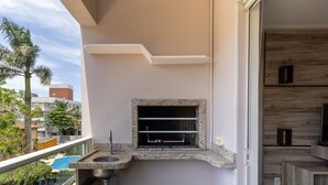Un balcón con pileta integrada, una ventana pequeña y vistas de los edificios y árboles circundantes.