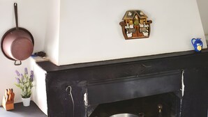 A kitchen with a black stove, a hanging pot, a red bucket, a potted plant, and a wall-mounted light fixture. - Apartment 'Casa 6 Posti Letto' with Mountain View, Shared Garden and Balcony (Piana)