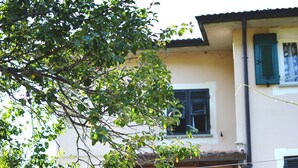 A two-story building with a balcony, a staircase, and a hanging flower pot. - Apartment 'Casa 6 Posti Letto' with Mountain View, Shared Garden and Balcony (Piana)