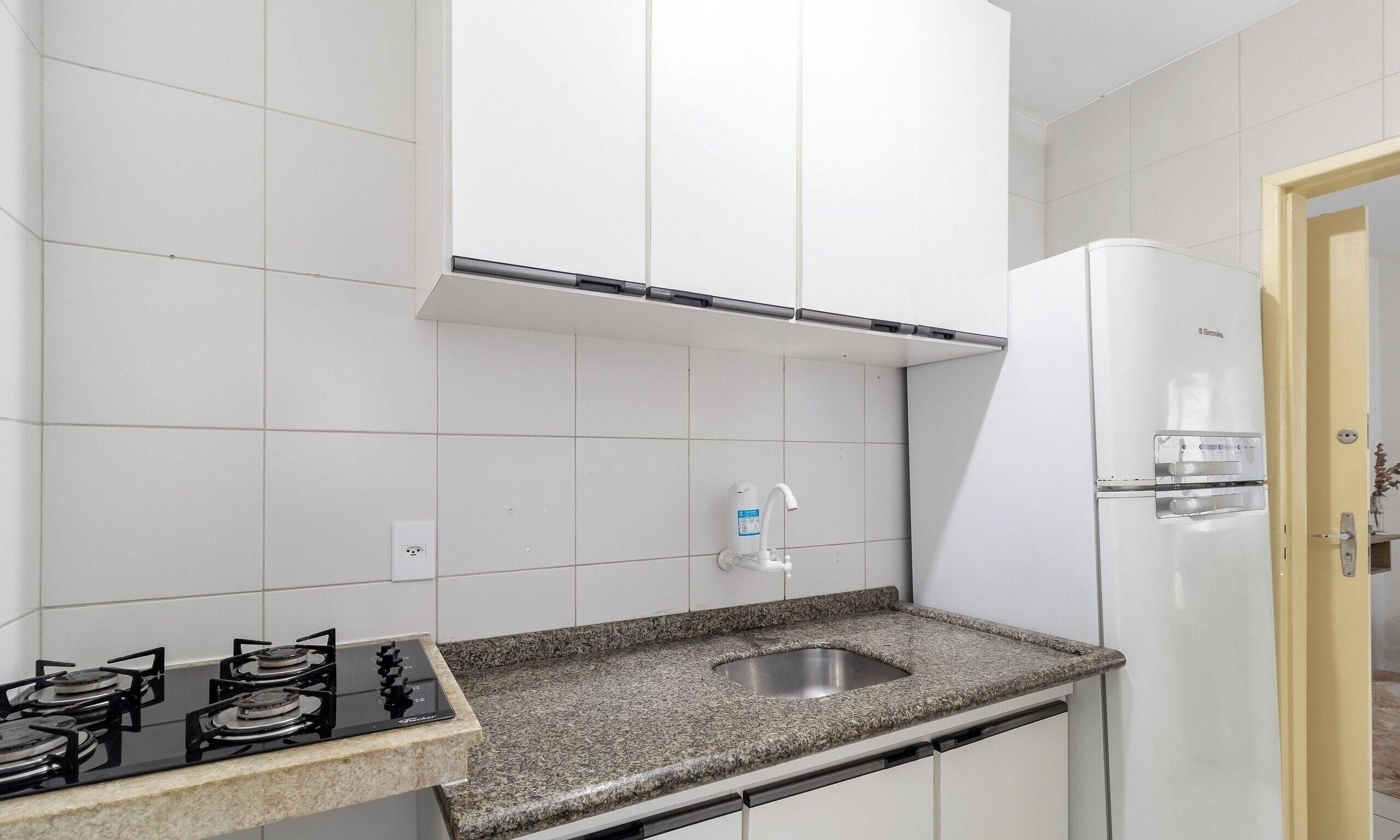 A kitchen with white cabinets, a granite countertop, a stainless steel sink, a gas stove, and a white refrigerator.