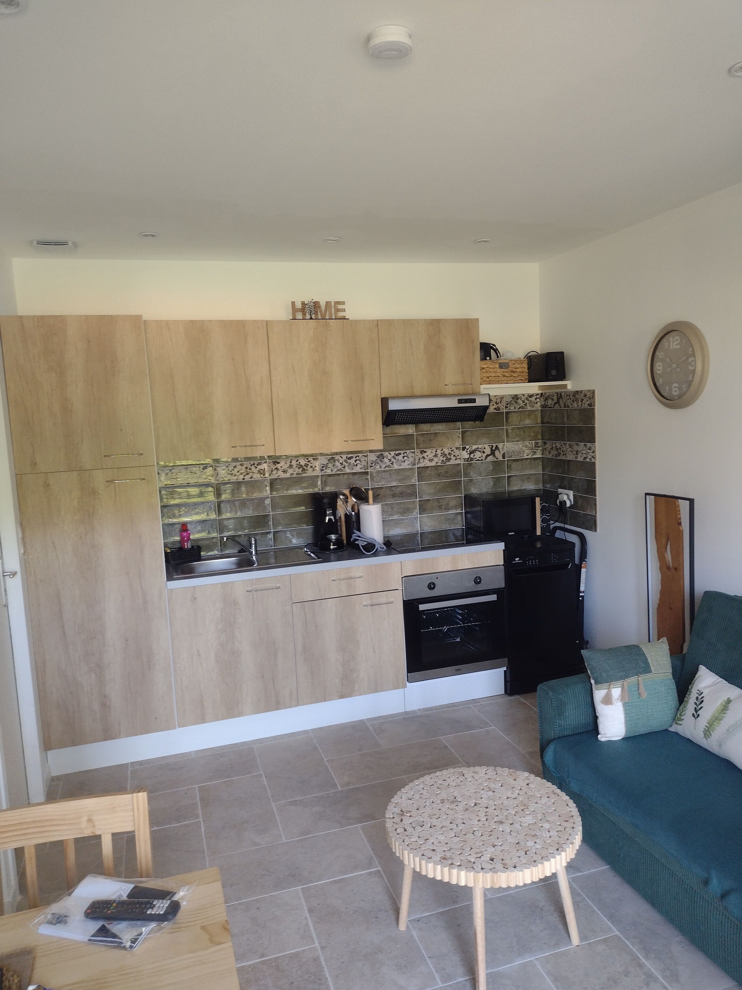 A modern kitchen with wooden cabinets, a built-in oven, and a coffee machine.