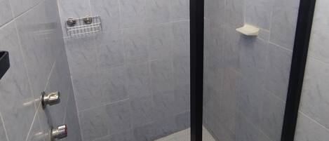 A small, enclosed shower area with a glass door, tiled walls, and a window above the shower.