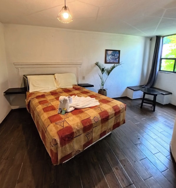 A neatly made bed with a patterned bedspread, a bedside table with a lamp, a potted plant, and a window with curtains. - PALACIO DE LOS ANGELES (Puebla)