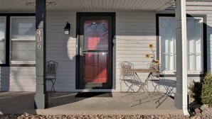 A house with a front door, number 406, two chairs, a table, and a small garden. - Casa del Toro (North Newton)