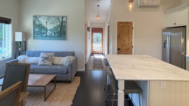 A modern kitchen with a marble countertop, pendant lighting, and a view into the dining area.