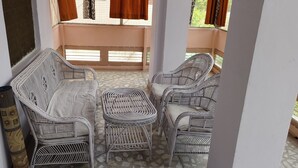 Un balcon agrémenté de meubles en osier, notamment d’un canapé et de fauteuils, ainsi que d’un tapis à motifs.