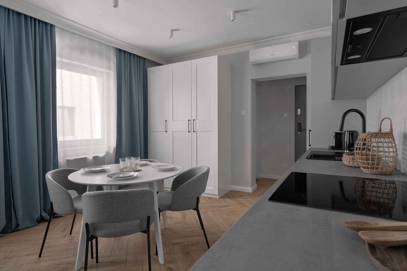 Una cucina moderna con mobili bianchi, un tavolo da pranzo con sedie e un'isola con lavello e bollitore.