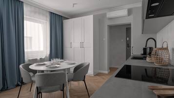 Una cucina moderna con mobili bianchi, un tavolo da pranzo con sedie e un'isola con lavello e bollitore.