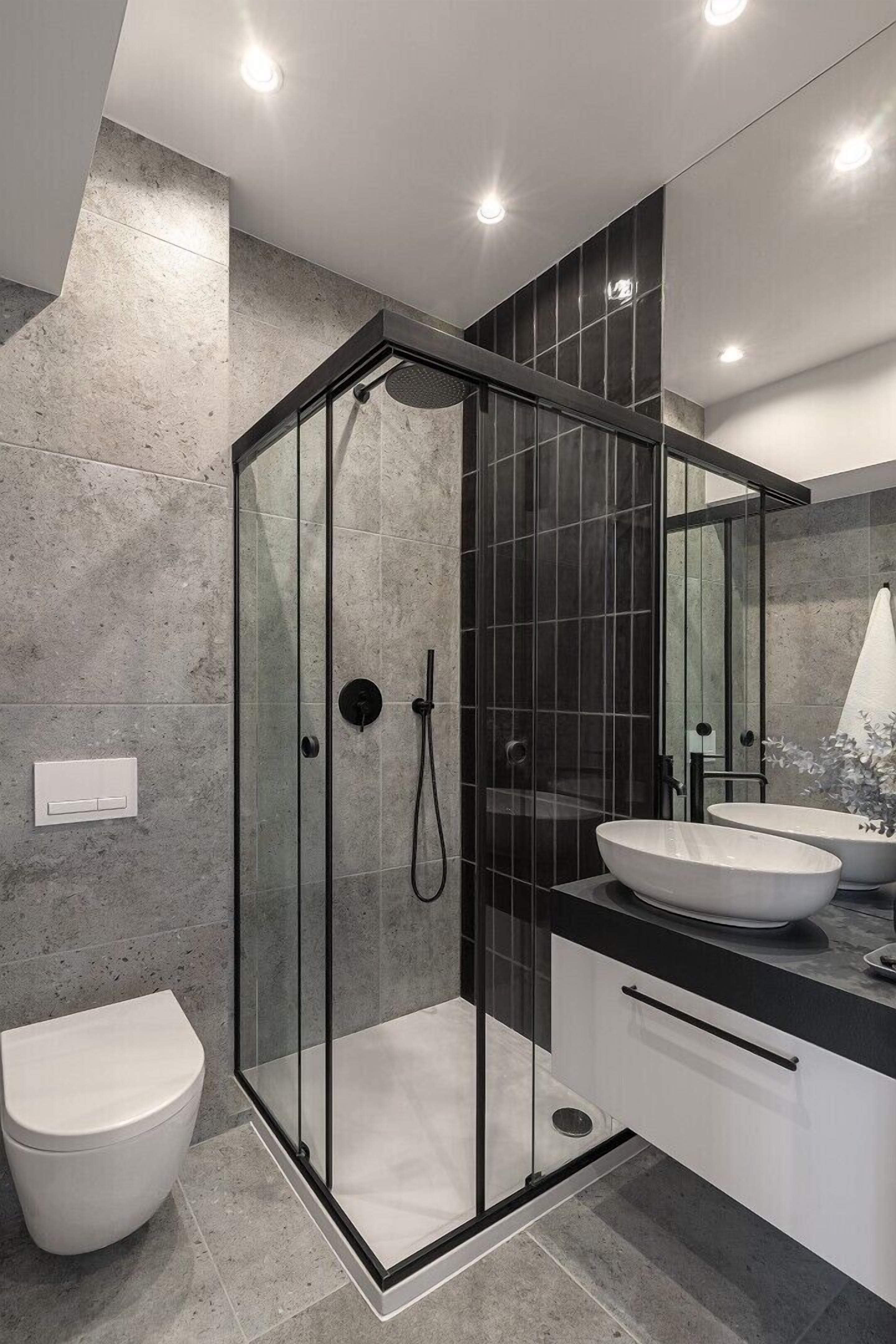 Un bagno moderno con doccia vetrata, un water bianco e un mobile lavabo con due lavandini.