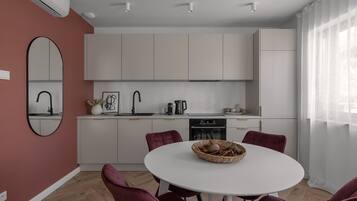 A modern kitchen with white cabinets, a round dining table with purple chairs, and a large mirror on the wall.