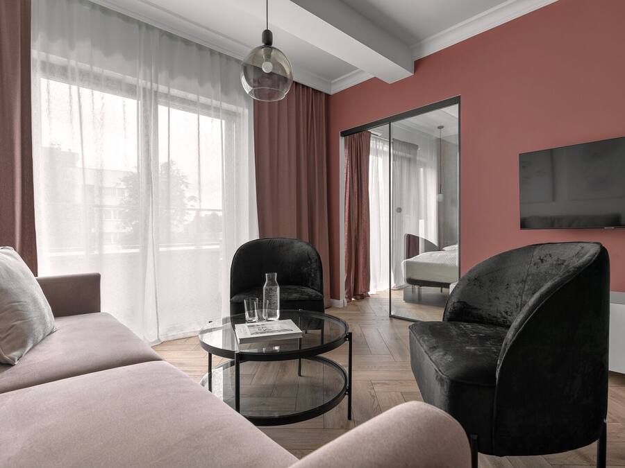 Een moderne woonkamer met een bank, twee fauteuils, een salontafel en een aan de muur bevestigde televisie.