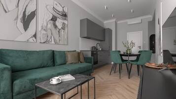 Een moderne woonkamer met een groene bank, een salontafel en een eethoek met groene stoelen.