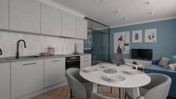 Una cocina moderna con armarios blancos, un grifo negro y una zona de comedor con una mesa blanca y sillas grises.