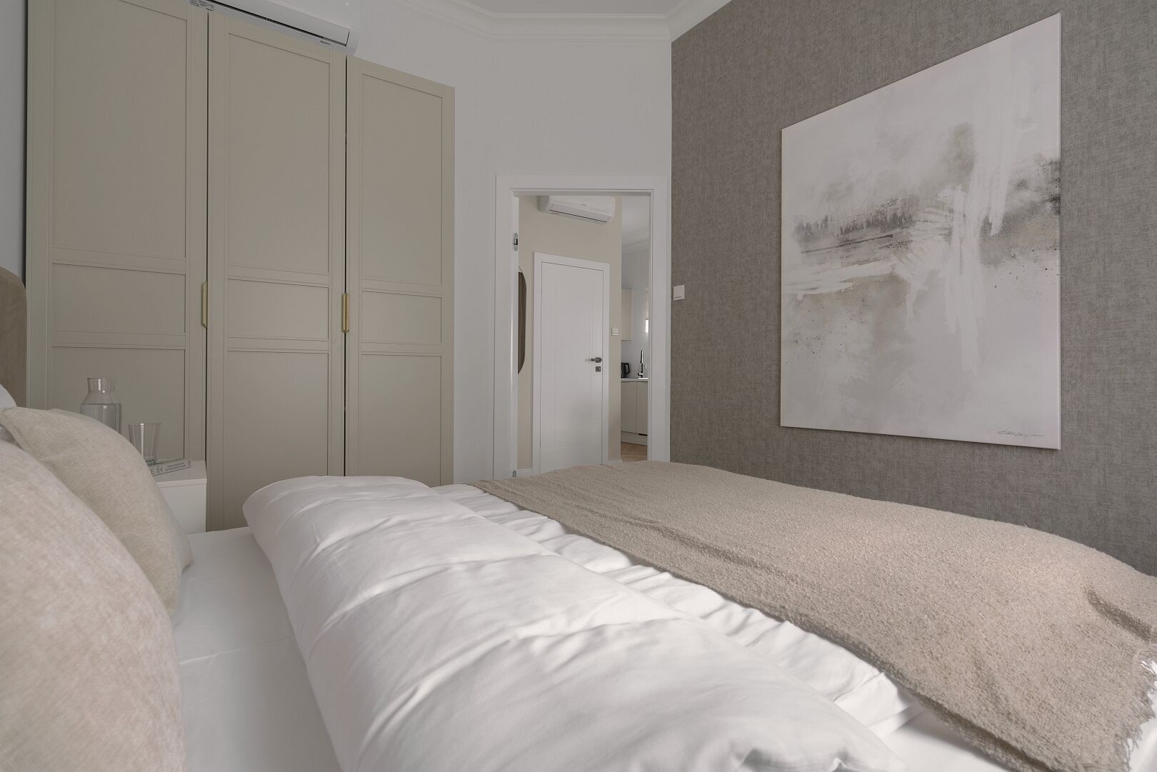 Un dormitorio con cama, armario y un cuadro en la pared.