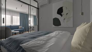 Ein modernes Hotelzimmer mit einem großen Bett, einem Schreibtisch, einer Couch und einem großen Fenster mit Vorhängen.