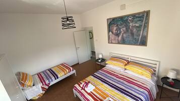 Ein Schlafzimmer mit einem Bett, einem Nachttisch, einer Lampe, einem Bild an der Wand und einer Tür.