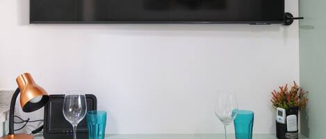 A dining setup with a television mounted on the wall, a lamp, and two sets of tableware.