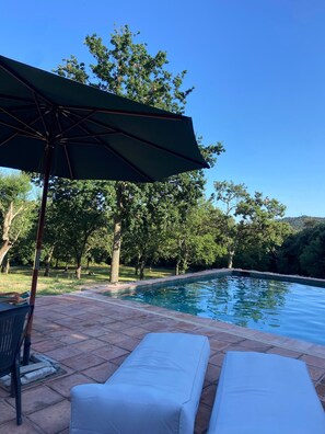 A swimming pool with lounge chairs and an umbrella, surrounded by trees. - Country House 'Rocosa' with Mountain View, Wi-Fi and Air Conditioning (San Acisclo de Vallalta)