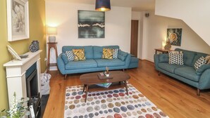 A living room with two sofas, a coffee table, a fireplace, and a polka dot rug. - No 39 (Ashbourne)
