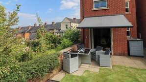 A residential property with a patio area featuring wicker furniture and a glass table. - No 39 (Ashbourne)