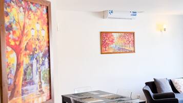 Una habitación con una mesa de comedor, sillas, un sofá y dos cuadros en la pared.