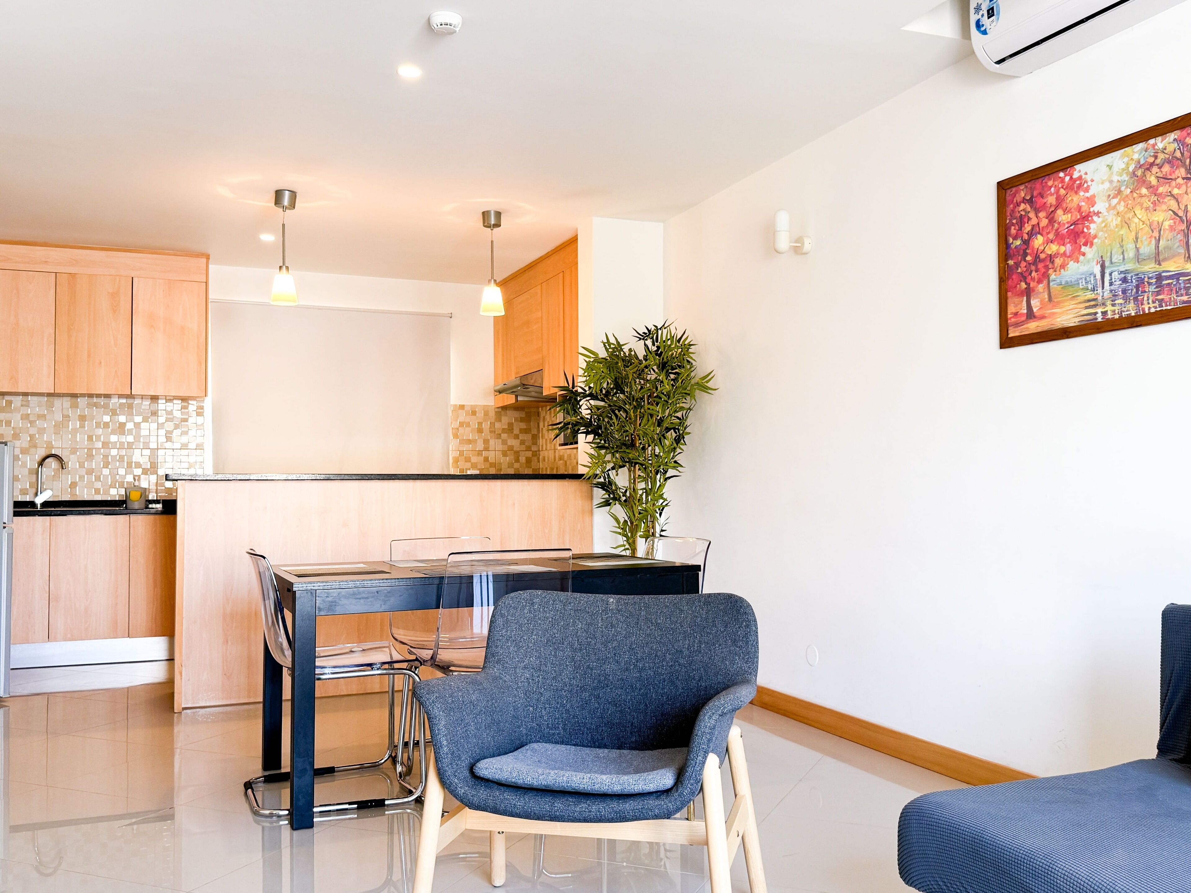 A modern kitchen with wooden cabinets, a dining table with chairs, and a potted plant.