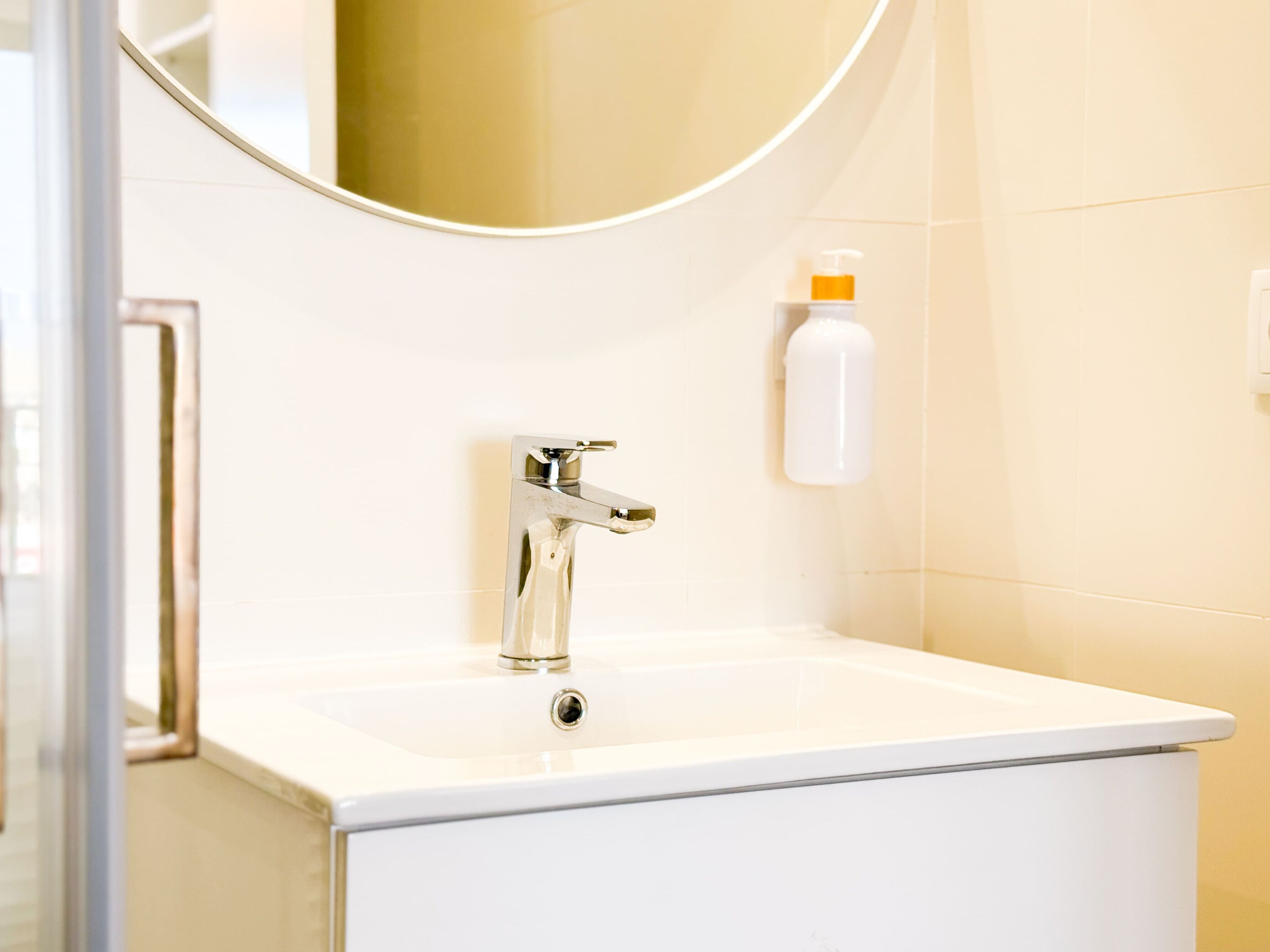 A bathroom with a white sink, chrome faucet, and a mirror above it.