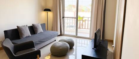 Una sala moderna con sofá, reposapiés y mueble para televisión.