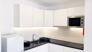 A modern kitchen with white cabinets, a black countertop, a built-in microwave, and a Westpoint refrigerator.