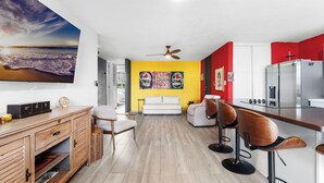 A modern kitchen with a central island, a dining area with bar stools, a sofa, and a ceiling fan. - Tropical Escape With Pool Tennis Cabo Rojo (Cabo Rojo)