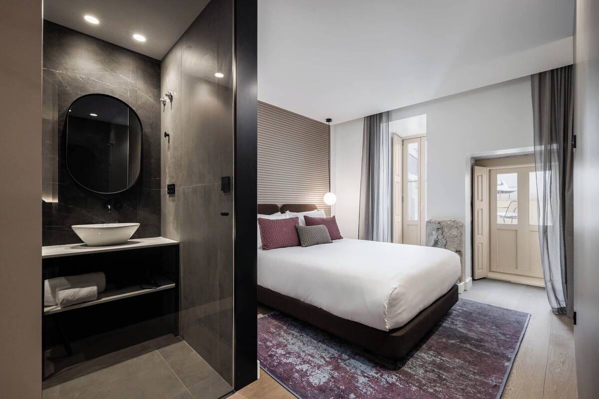Una habitación de hotel moderna con una cama grande, un lavamanos integrado y un espejo amplio.