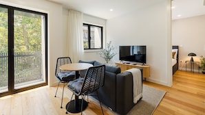 Un salon moderne avec un canapé, des fauteuils, un téléviseur et un balcon.