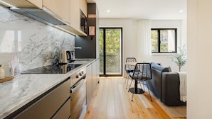 Une cuisine moderne avec un plan de travail en marbre, un four encastré et une chaise noire placée à une table à manger.