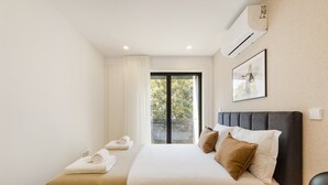 Une chambre à coucher avec un lit, une fenêtre, un appareil de climatisation et un tableau encadré au mur.