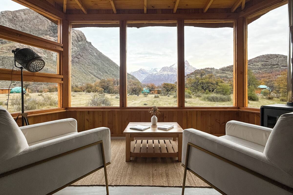 A cozy room with wooden walls and large windows offering a mountain view.