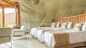 Un dormitorio amplio con techo alto, cabecera de madera y un ventanal con vistas al exterior.