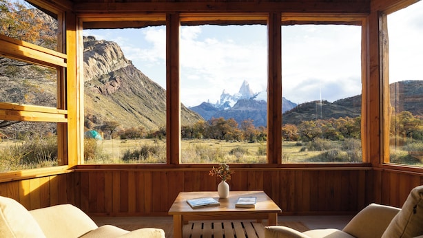 Una habitación acogedora con paredes de madera y ventanas grandes que ofrecen vistas a montañas y un valle.