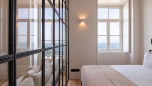 A bedroom with a large window, a bed, and a view of the sea. - Luz 147 | Seaside Oasis by LovelyStay (Porto)