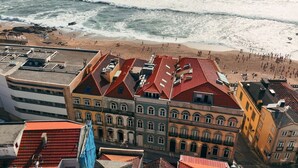 A coastal cityscape with buildings featuring red-tiled roofs and a beach in the background. - Luz 147 | Seaside Oasis by LovelyStay (Porto)