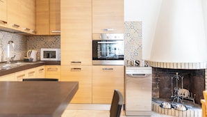 Cozinha moderna com armários de madeira, forno embutido, micro-ondas e máquina de lavar louça.