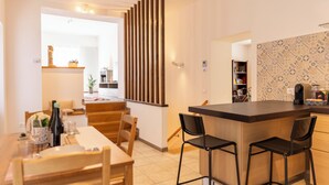 Uma cozinha moderna com uma ilha de madeira, banquetas de bar e uma área de jantar com mesa e cadeiras.