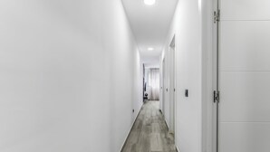 Un couloir d’hôtel moderne avec des murs blancs et un plancher en bois.