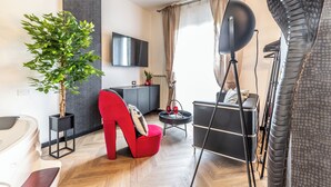 Un salon moderne avec une chaise haute rouge, un canapé noir, une plante en pot, un téléviseur à écran plat et une grande sculpture de serpent.